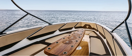 Bow lounge with beige cushions and teak table on the Navy Blue Raptor