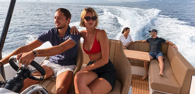 Friends cruising on Ryck luxury open-yacht by Navy Blue, one at the helm and guests relaxing on the deck