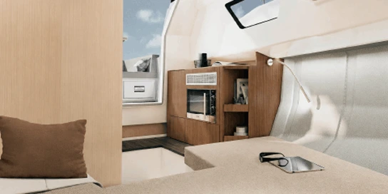 Navygon yacht interior cabin by Navy Blue with a bed, beige bedding, pillows, a skylight hatch, and warm wood paneling