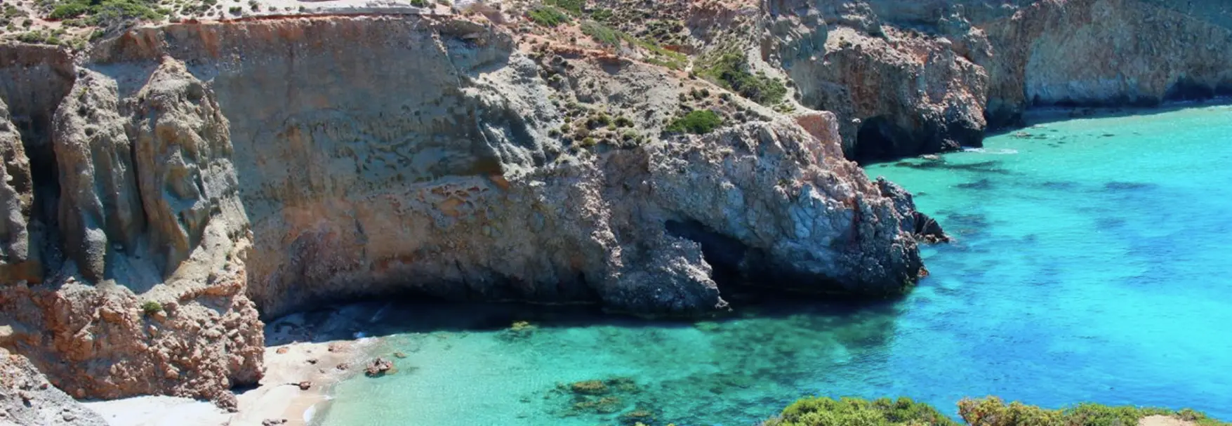 Amber cliffs and turquoise shallows at Tsigrado, a hidden cove on the southern coast of Milos