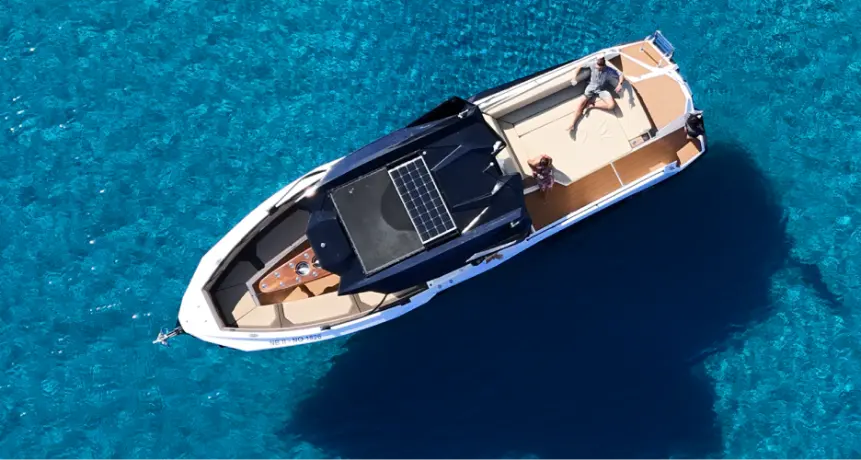Guests relaxing on Navy Blue luxury yacht deck in crystal-clear turquoise waters off Milos