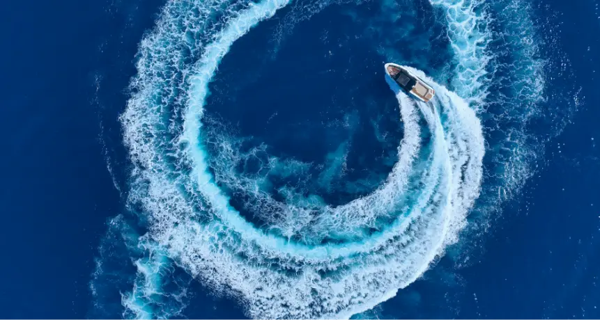 Aerial view of Navy Blue yacht creating spiral wake patterns in the deep blue Aegean Sea off Milos