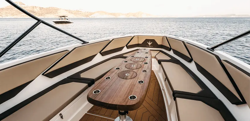 Bow lounge with V-shaped seating and teak table on the Navy Blue Raptor overlooking Milos