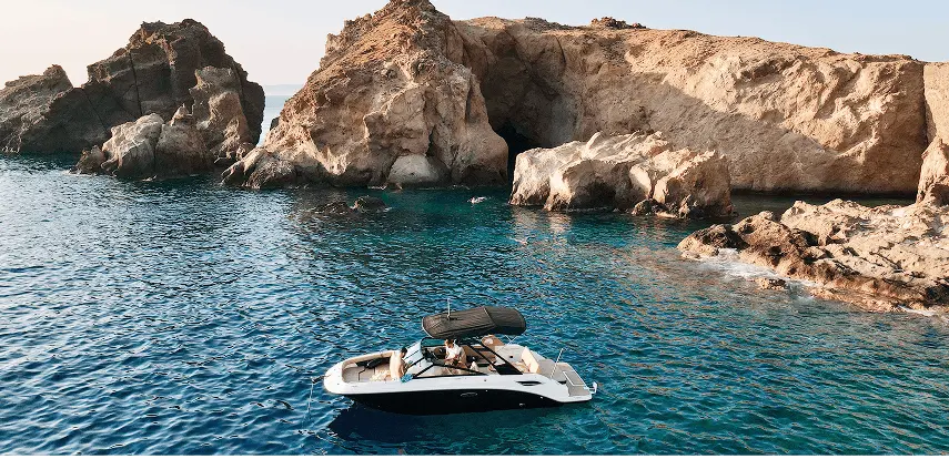 Navy Blue Sea Ray all’ancora vicino a grotte marine vulcaniche a Milos con ospiti che fanno snorkeling