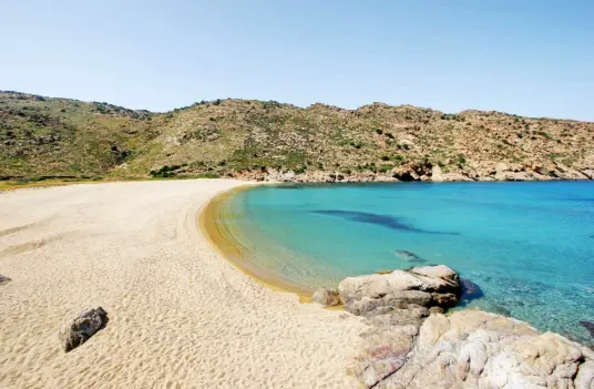 The wide sandy sweep of Mylopotas beach on Ios, with clear shallow water and bare hills behind