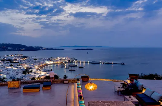 Twilight view over Mykonos old port with boats anchored in the harbor and the Aegean stretching toward the Cyclades.