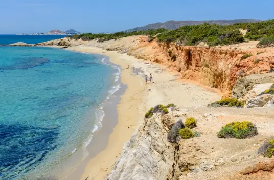 Beach with red cliffs File name: naxos-beach-sandy-coast.png Alt text: Sandy Naxos beach with red cliffs and clear Aegean water along the island's coast