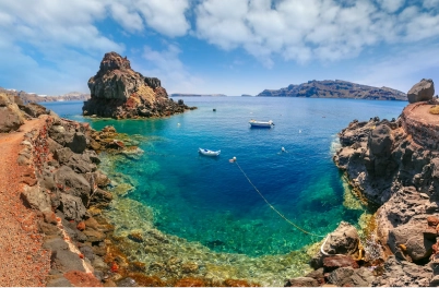 Hidden Aegean swim cove with turquoise water, volcanic rocks, and small boats moored near the shore, by Navy Blue