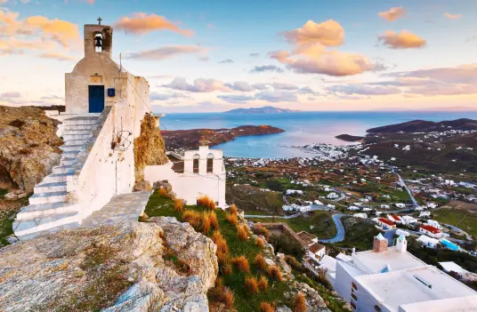 A small white chapel on the rocks above the Chora of Serifos, with the bay below at dusk