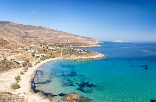Psili Ammos beach on Serifos, a pale sandy curve meeting clear turquoise water and open hills