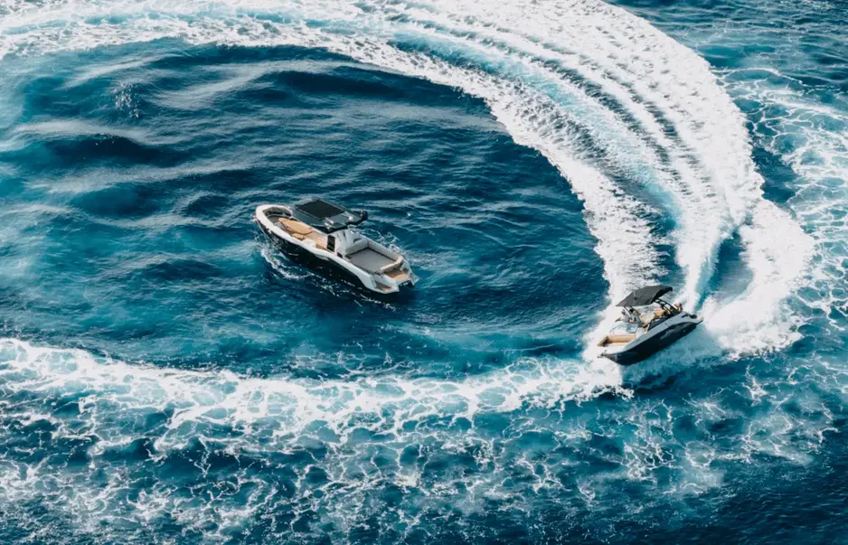 Aerial view of two Navy Blue open-yachts cutting through vivid blue Mediterranean waters during a semi-private cruise in Milos
