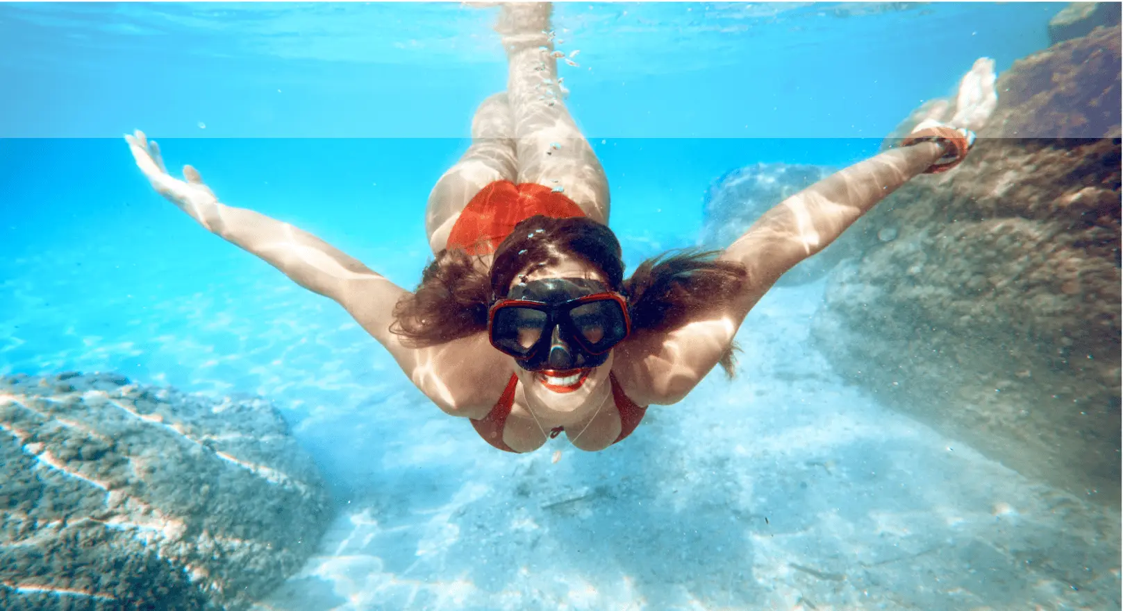 Snorkeler gliding through clear blue waters above the sandy seabed off the coast of Milos