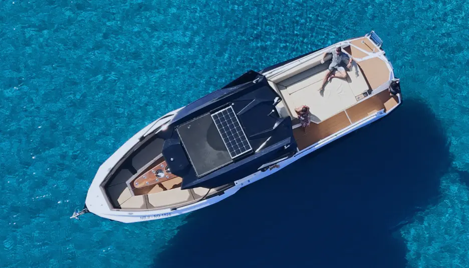 Guests relaxing on Navy Blue luxury yacht deck in crystal clear turquoise waters off Milos