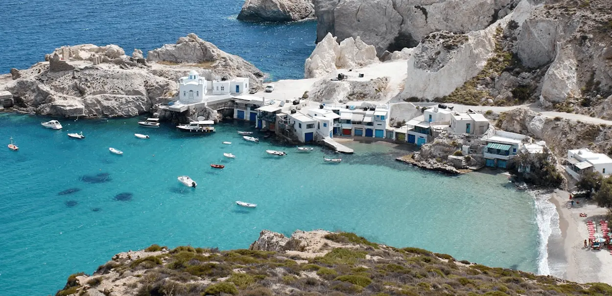 Whitewashed fishing village and turquoise bay on the Milos coastline in the Cyclades